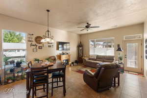 Dining area with a textured ceiling, a ceiling fan, tile patterned flooring, and a fireplace