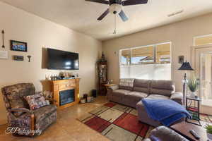 Living room featuring a fireplace, tile patterned floors, and a ceiling fan