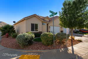 View of front of property with a tile roof, stucco siding, a garage, and driveway
