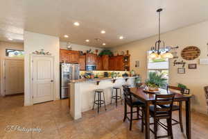 Kitchen featuring a peninsula, brown cabinetry, a breakfast bar, recessed lighting, and appliances with stainless steel finishes
