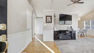 Living room with light wood-style floors, a ceiling fan, arched walkways, and high vaulted ceiling