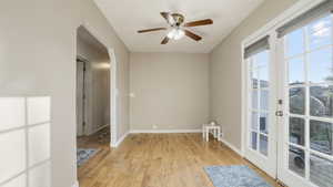 Empty room with light wood-style floors, arched walkways, and a ceiling fan