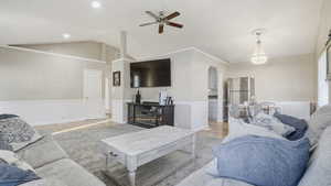 Living area featuring lofted ceiling, wood finished floors, ceiling fan, arched walkways, and crown molding