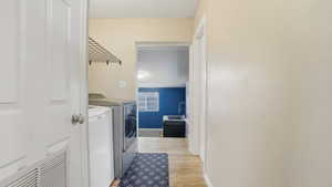 Laundry area featuring separate washer and dryer and light wood finished floors