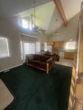 Living room featuring high vaulted ceiling, a ceiling fan, carpet, beamed ceiling, and light tile patterned floors