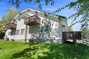 View of Condo's exterior featuring a Balcony, deck, lawn, and stucco siding