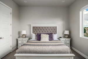 Bedroom featuring dark colored carpet and baseboards