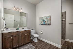 Full bathroom featuring vanity, dark wood finished floors, and a tile shower