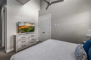 Bedroom with carpet, ceiling fan, and a high ceiling