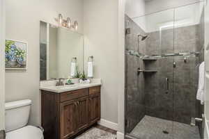 Bathroom with vanity, a stall shower, and dark wood-type flooring