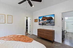 Carpeted bedroom featuring connected bathroom, ceiling fan, and wood finished floors