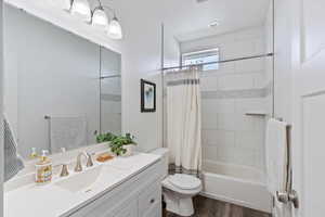 Full bathroom with shower / bath combo, vanity, and dark wood-style floors