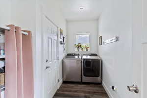 Laundry area with dark wood-style flooring and washing machine and dryer