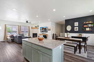 Kitchen with light stone countertops, recessed lighting, dark wood finished floors, a kitchen island, and open floor plan