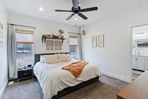 Bedroom with dark colored carpet, multiple windows, a ceiling fan, recessed lighting, and connected bathroom