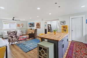 Kitchen featuring butcher block countertops, open floor plan, a center island, recessed lighting, and light wood-style flooring