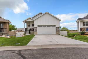 View of front of property featuring concrete driveway, board and batten siding, covered porch, and a garage