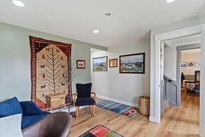 Living area featuring light wood-style flooring, recessed lighting, and stairway