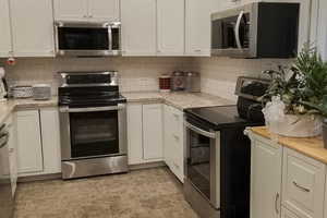 Kitchen with stainless steel appliances, light countertops, and white cabinetry