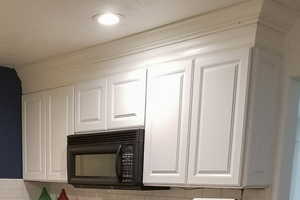 Kitchen view of white cabinetry, black microwave, and tasteful backsplash