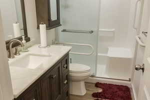 Bathroom with a stall shower, vanity, and wood finished floors