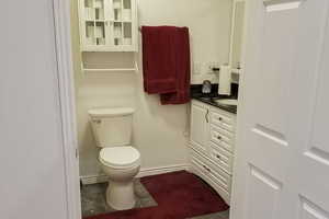 Half bath with dark tile patterned flooring and vanity