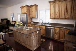 ADU - Kitchen with appliances with stainless steel finishes, an island with sink, dark wood-type flooring, an open floor plan, and a kitchen bar