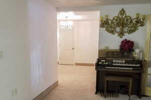 Corridor with a chandelier and light colored carpet