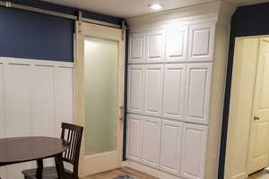Kitchen with a barn door, wood finished floors, wainscoting, and a decorative wall