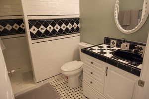 ADU - A second  bathroom that features a stall shower, a vanity, and light-patterned tile flooring