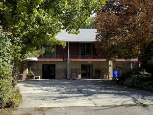 View of front of home with a balcony and stone siding