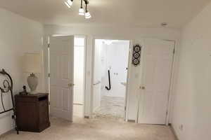 Corridor with light colored carpet and baseboards