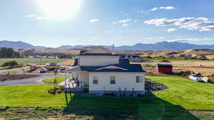 View of side of property featuring a mountain view, a lawn, and a patio