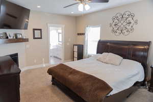 Master bedroom featuring light carpet, multiple windows, a ceiling fan, ensuite bathroom, and recessed lighting