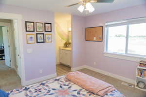Bedroom with light colored carpet, ensuite bath, and a ceiling fan