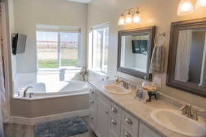 Master bathroom with double vanity, a bath, and LVP floors