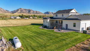 Back of house with a yard, a patio, a balcony, and a mountain view