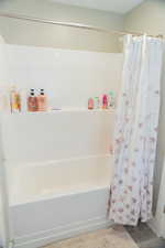 Bathroom featuring light wood-style floors and shower / tub combo with curtain