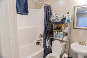Bathroom featuring shower / tub combo with curtain and toilet