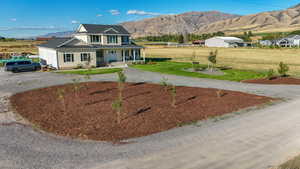 View of front of property with covered porch, driveway, a mountain view, and a front yard