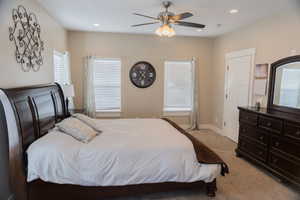 Master bedroom featuring light carpet, a ceiling fan, and recessed lighting and ensuite bathroom