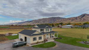 View of front of home with gravel driveway, covered porch, a front yard, a mountain view, and a garage