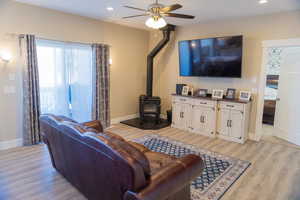 Living room featuring a wood stove, recessed lighting, LVP flooring, and ceiling fan