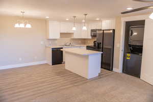 Basement apartment kitchen/dining area with white cabinets, black appliances, light countertops, recessed lighting, and hanging light fixtures