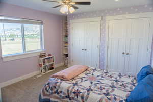 Bedroom featuring multiple closets, carpet floors, and ceiling fan