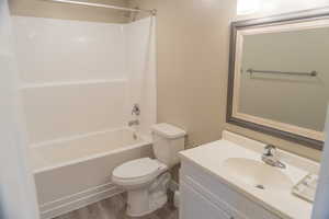 Bathroom featuring washtub / shower combination, vanity, and dark wood-style floors