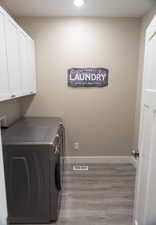 Laundry room featuring light wood-style floors, washer and clothes dryer, cabinet space, and recessed lighting