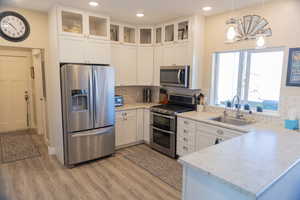 Kitchen featuring pendant lighting, appliances with stainless steel finishes, light countertops, white cabinetry, and tasteful tiled backsplash