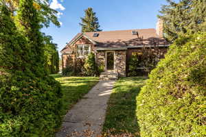 View of front of house with a front yard, a chimney, brick siding, and a shingled roof
