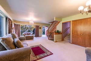 Carpeted living area with a chandelier and stairway